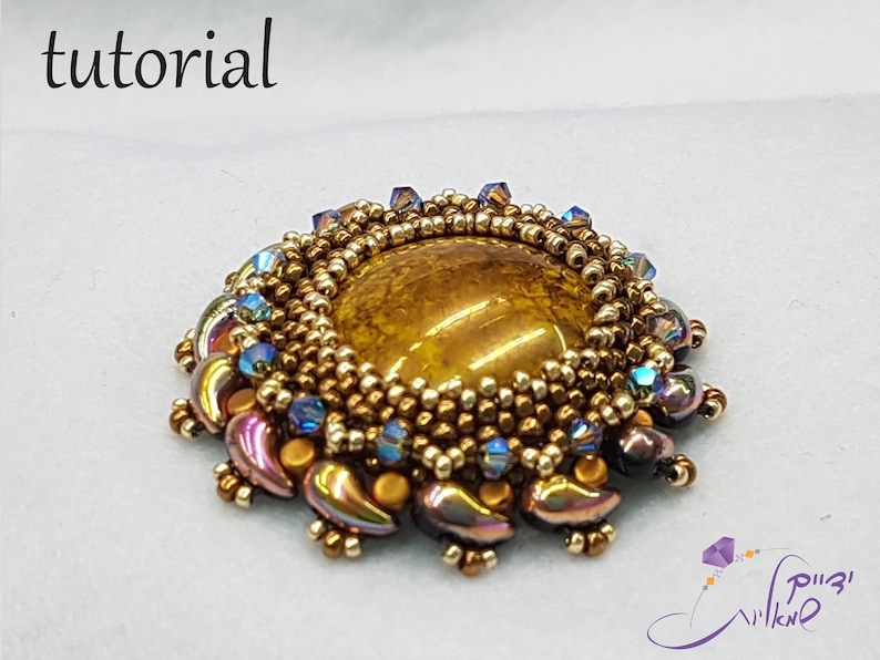 May include: A gold and brown beaded brooch with a large, round, brown gemstone in the center. The brooch is surrounded by smaller, iridescent beads in shades of purple, blue, and gold.