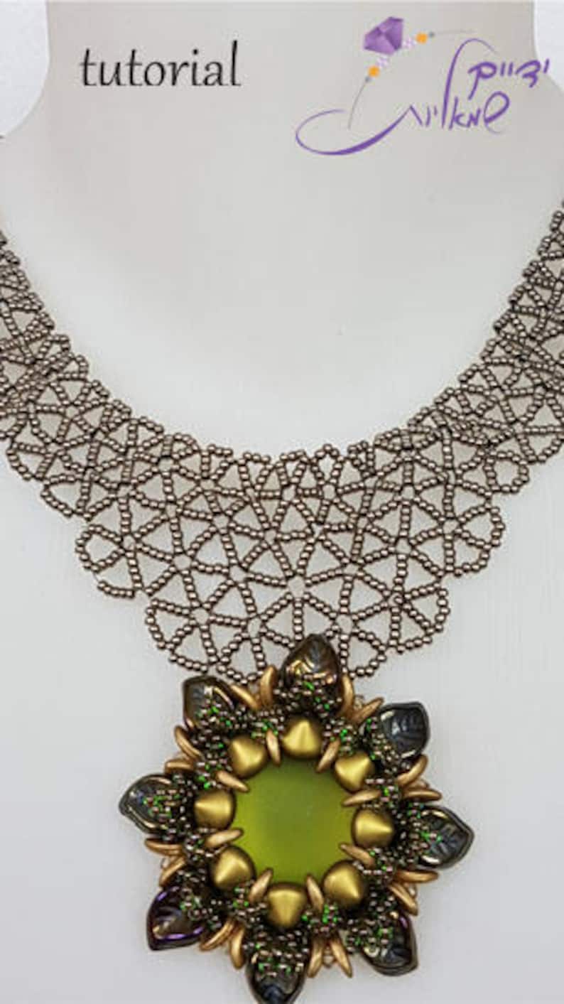 May include: A silver beaded necklace with a large, green and gold beaded flower pendant. The pendant has a green glass center and is surrounded by gold and green beads.