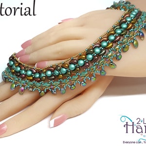 May include: A turquoise, brown, and gold beaded bracelet with a leaf design. The bracelet is on a hand with white nail polish. The image includes the text "tutorial" and "2-Left Hands".