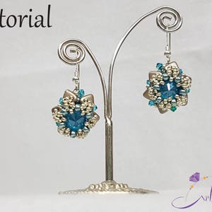 May include: A pair of silver earrings with blue and gold bead clusters. The earrings are displayed on a silver stand.