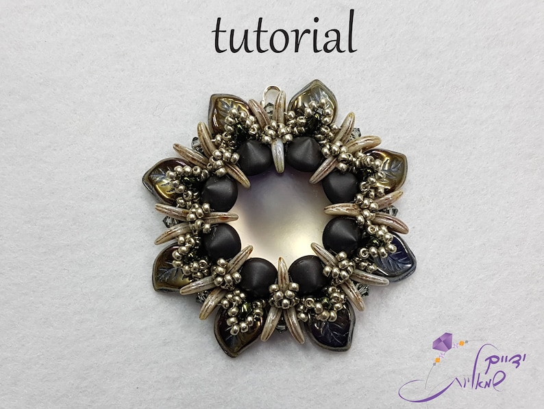 May include: A black and brown beaded pendant with a silver-colored ring in the center. The pendant is shaped like a flower with a circular center.
