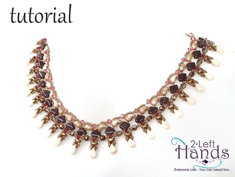 May include: A beaded necklace with a multi-colored design featuring brown, pink, and white beads. The necklace has a fringe of white beads at the bottom. The text "2 Left Hands" is visible in the lower right corner of the image.
