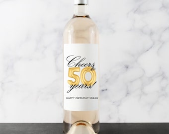 May include: A clear wine bottle with a silver cap and a white label. The label reads "Cheers to 50 years!" with a gold foil "50" balloon design. Below the text is "HAPPY BIRTHDAY SARAH".