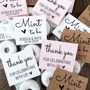 May include: A collection of mint candies in clear plastic packaging, each accompanied by a small square tag. The tags are in various colors, including pink, white, and brown, with the words "Mint to be" and "thank you" printed on them.