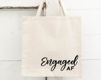 May include: A white canvas tote bag with black text that reads "Engaged AF".