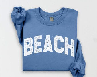 May include: A blue sweatshirt with the word "BEACH" printed in white on the front. The sweatshirt has a distressed look.