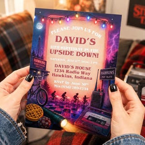 May include: A rectangular birthday invitation card featuring a dark, neon-lit scene with a radio tower, a bicycle, a waffle, a die, a flashlight, and a cassette tape. The text reads: Please join us for David's 11th birthday in the Upside Down!