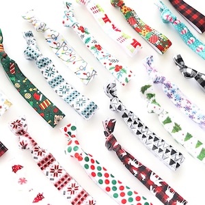 May include: A collection of colorful Christmas-themed hair ties with various patterns, including snowflakes, reindeer, and Christmas trees.