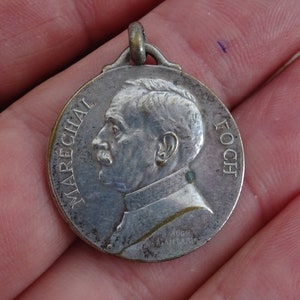 May include: A silver medal with a profile portrait of a man and the text "MARÉCHAL FOCH" around the edge.