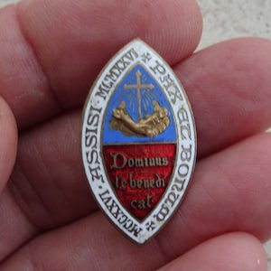 May include: A white, gold, blue, and red enamel pin with the text "Pax et Bonum MCMXXI" and "Domine te Benedicat" in gold lettering.