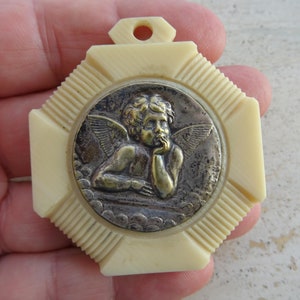 Religious antique French catholic bakelite Art Deco cradle medal charm medallion pendant of a cherub Guardian Angel Raphael. K 48