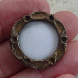 May include: A small, oval-shaped brass picture frame with a decorative, ornate design. The frame has a white background and is ready for a photo.