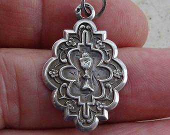 May include: Silver pendant with a chalice design, surrounded by floral details. The pendant has a loop at the top for attaching to a chain.