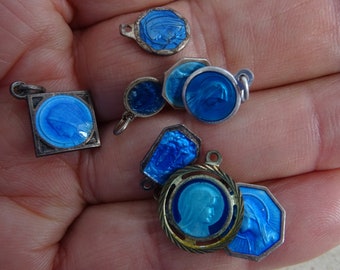 May include: A collection of seven small blue enamel pendants featuring the image of the Virgin Mary. The pendants are made of silver and have different shapes and sizes.