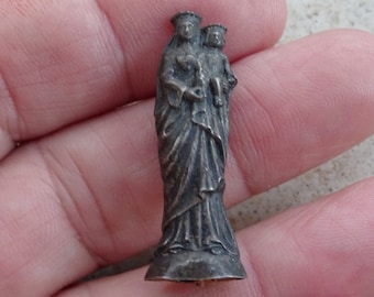 May include: Silver-toned figurine of the Virgin Mary holding a baby Jesus. The figurine is detailed and has a crown on the Virgin Mary's head.
