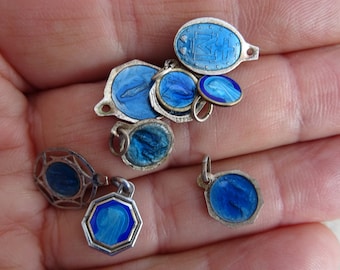May include: A collection of vintage blue enamel charms with silver settings. The charms feature religious imagery and are perfect for adding a touch of faith to jewelry.