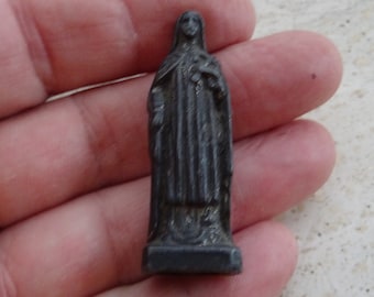 May include: A small, black metal figurine of a woman wearing a long robe. The figurine is about 2 inches tall and has a simple, classic design.