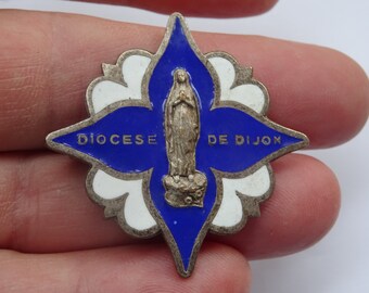 May include: A blue and white enamel pin with a depiction of the Virgin Mary and the text "DIOCESE DE DIJON".