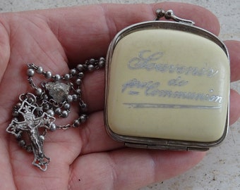 以下が含まれることがあります： 十字架のペンダントが付いた銀のロザリオと、「Souvenir's first Holy Communion」という碑文が刻まれた小さな白い箱。