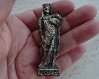 May include: Silver-toned metal figurine of the Virgin Mary holding a baby Jesus. The figurine is standing on a base with the inscription "SVD. PARIS"