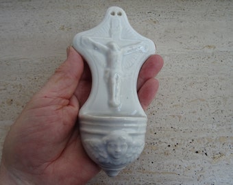 Peut inclure: Fontaine d'eau bénite murale en céramique blanche avec une image sculptée de Jésus sur la croix et un ange en bas.