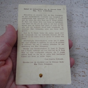 Puede incluir: Una tarjeta de oración blanca con texto negro. El texto dice "Gebed tot verheselijking van de Dienaar Gods Mgr. Victor SCHEPPERS" e incluye una oración a Dios por el difunto.