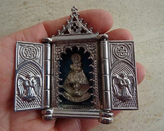 May include: A silver religious shrine with a hinged design. The central compartment features a statue of a religious figure against a blue backdrop. The side panels depict angel figures.