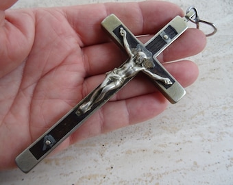 Puede incluir: Un crucifijo de plata y madera con una figura detallada de Jesucristo. El crucifijo tiene un bucle en la parte superior para colgar.