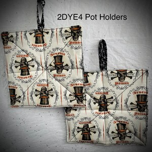 May include: Two square pot holders with a repeating pattern of skulls wearing top hats, crossbones, and the words "Arsenic" and "Poison." The pot holders have black and white patterned hanging loops and are quilted.