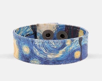 May include: A blue and yellow canvas wristband with a print of Vincent van Gogh's Starry Night. The wristband has two black snap buttons.