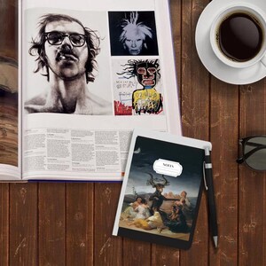 Peut inclure: Un carnet noir et blanc avec le mot "NOTES" imprim&eacute; sur la couverture. Le carnet est ouvert sur une page avec une illustration en noir et blanc d'une sc&egrave;ne d'un tableau. Le carnet est pos&eacute; sur une table en bois avec une tasse de caf&eacute;, un magazine et des lunettes de soleil.