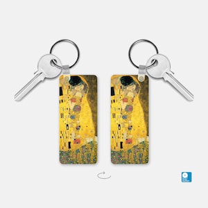 May include: A pair of silver keychains with a rectangular image of Gustav Klimt's The Kiss painting. The image is in a gold and yellow color scheme with a black outline.