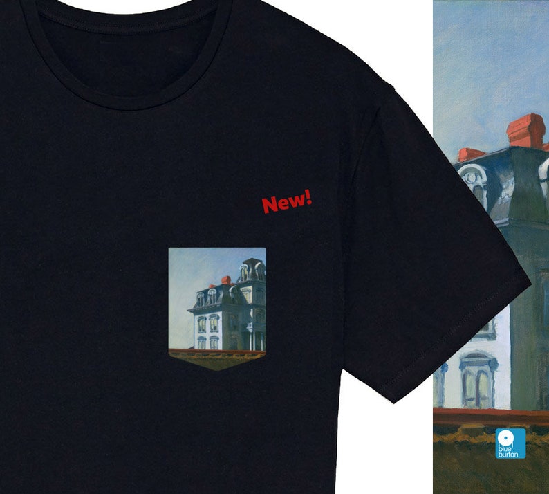 Peut inclure: Un t-shirt noir avec une poche repr&eacute;sentant une peinture d'une maison. La poche porte l'inscription "New!" au-dessus.