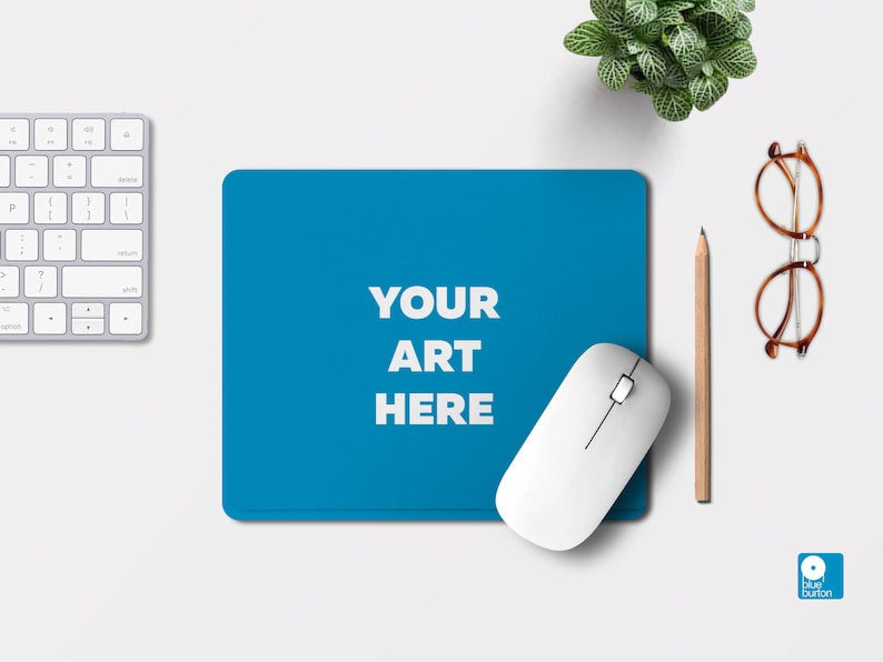 Pu&ograve; includere: Un tappetino per mouse blu con il testo "YOUR ART HERE" in bianco. Un mouse wireless bianco &egrave; sul tappetino per mouse. Una matita e degli occhiali sono su una superficie bianca.