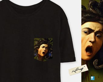 May include: Black t-shirt with a pocket featuring a graphic of Medusa, a mythical Greek figure with snakes for hair, in a vintage style. The graphic is in a pocket on the left side of the shirt.