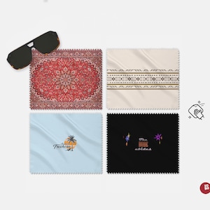 May include: Four different microfiber cleaning cloths with various designs. The designs include a red, white, and blue patterned rug, a beige cloth with a black and white geometric pattern, a light blue cloth with a palm tree and the text "Jungle Treechom", and a black cloth with the text "The Dude abides" and purple stars.