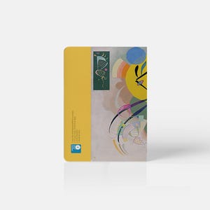 Pu&ograve; includere: Un quaderno giallo con un design astratto colorato sulla copertina. Il design presenta un cerchio giallo, un cerchio blu e linee verdi. Il quaderno ha un piccolo quadrato verde sul retro con un design di una farfalla.