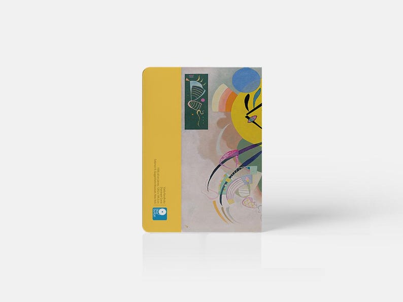 Pu&ograve; includere: Un quaderno giallo con un design astratto colorato sulla copertina. Il design presenta un cerchio giallo, un cerchio blu e linee verdi. Il quaderno ha un piccolo quadrato verde sul retro con un design di una farfalla.