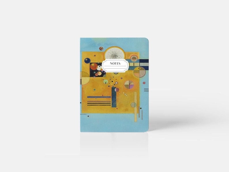 May include: A blue notebook with a yellow, orange, and red abstract painting on the cover. The painting features circles, squares, and lines. The notebook has the word "NOTES" printed on the cover.