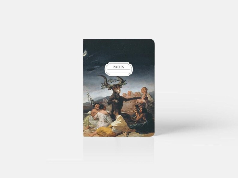 Peut inclure: Un carnet noir avec une peinture d'une figure sombre avec des cornes et une couronne de feuilles, entour&eacute;e de personnes. Le carnet porte l'inscription "NOTES" sur la couverture.