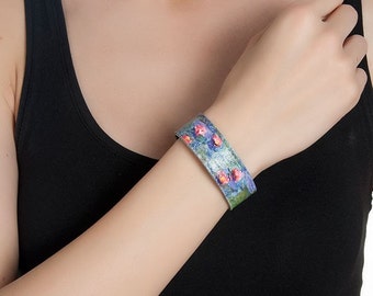 May include: A blue and purple leather bracelet with a floral print. The bracelet is worn on a person's wrist.
