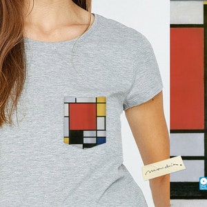 May include: A grey t-shirt with a pocket featuring a geometric design in red, yellow, blue, and black. The design is reminiscent of a famous abstract painting.