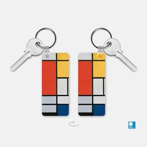 May include: A keychain featuring a colorful abstract painting with red, yellow, blue, and white squares. The keychain is made of metal and has a silver key ring.