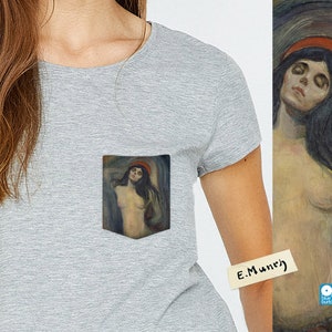 May include: A grey t-shirt with a pocket featuring a painting of a woman with long dark hair and a red hat. The painting is titled "E. Munch".