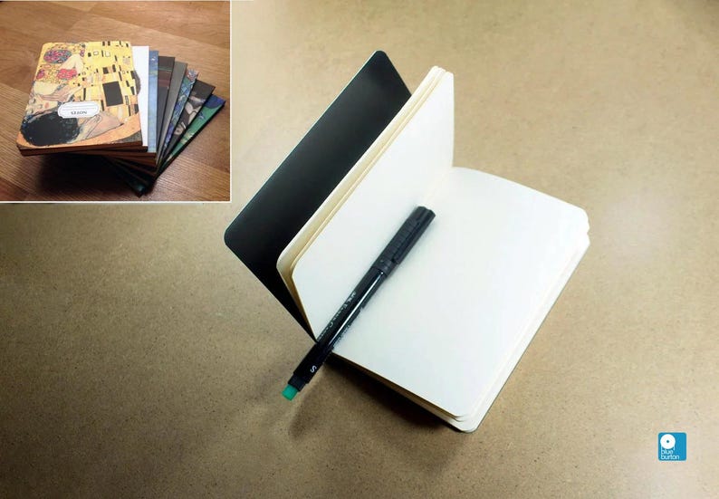 May include: A black notebook with a white interior and a black marker pen. The notebook is open and the marker is lying on the open pages.
