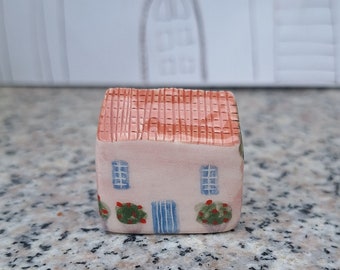 Pequeña casa de arcilla rosa pintada a mano, colorida casa de pueblo de cerámica