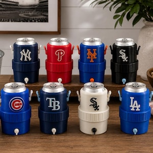 Może przedstawiać: Kolekcja ośmiu miniaturowych chłodziarek do napoj&oacute;w w kształcie puszek po napojach, z kt&oacute;rych każda zawiera logo drużyny Major League Baseball. Chłodziarki są ułożone w dw&oacute;ch rzędach i prezentują logotypy drużyn Yankees, Phillies, Mets, White Sox, Cubs, Rays oraz Dodgers.