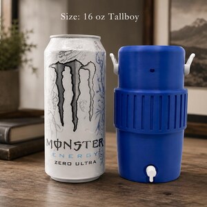 Może przedstawiać: Puszka Monster Energy Zero Ultra o pojemności 16 uncji z biało-srebrnym wzorem obok niebieskiej plastikowej chłodziarki do napoj&oacute;w z białym kranikiem i dwoma białymi uchwytami bocznymi. Tekst na puszce brzmi Monster Energy Zero Ultra.