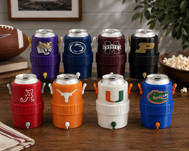 May include: A collection of eight cylindrical beverage coolers designed to hold standard cans, each featuring a unique collegiate sports logo. These plastic coolers include a top opening, side handles, and a small spigot at the base for dispensing.
