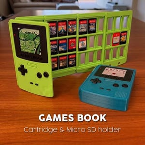 May include: A lime green Games Book cartridge and micro SD holder, shaped like a classic handheld game console, with a teal blue console next to it. The holder is filled with game cartridges. The text "GAMES BOOK" is visible.